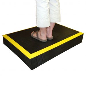 SmartCells ergo riser in black with yellow edges from a diagonal view with a person standing on it